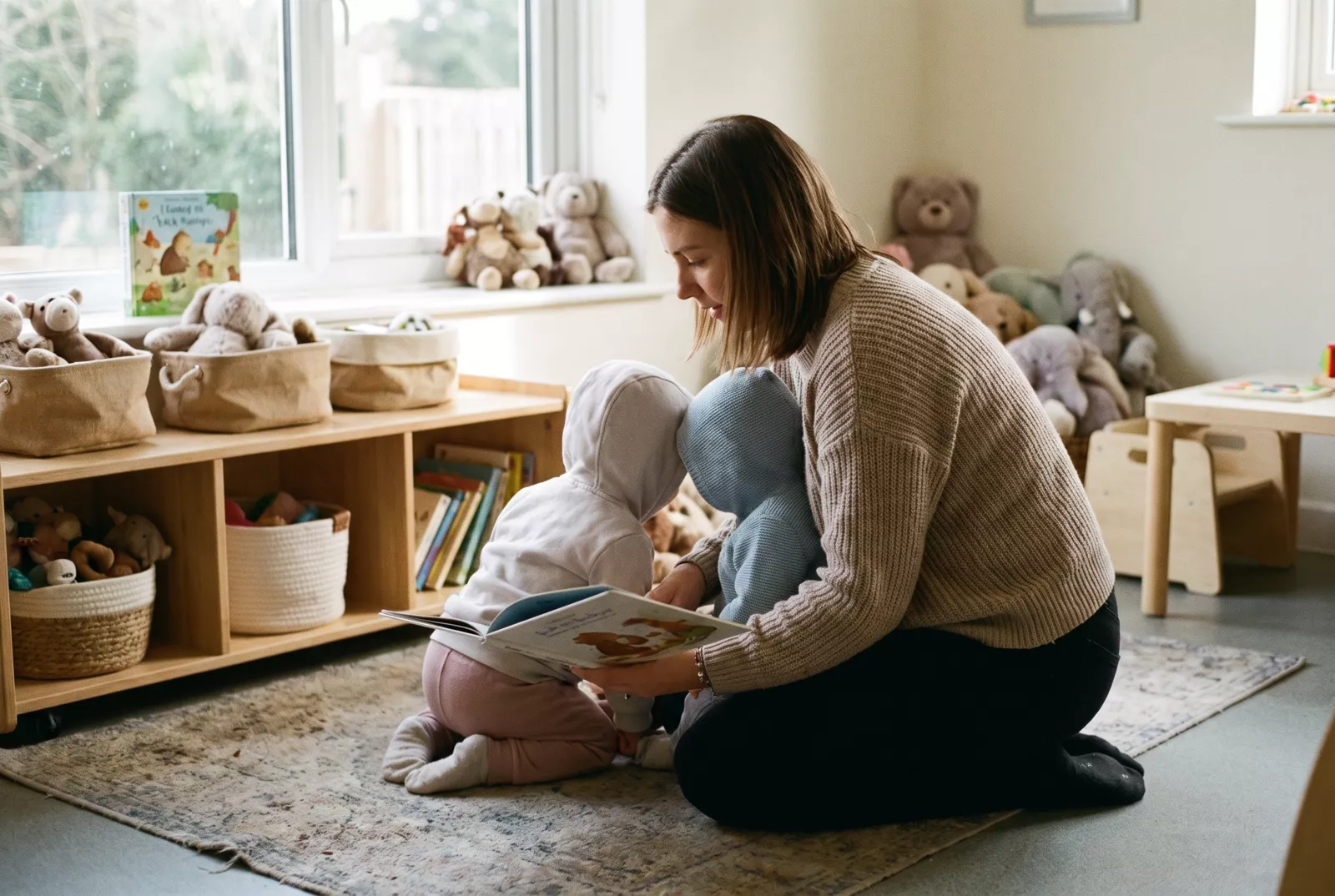 Nursery practitioner reading a picture book with toddlers
